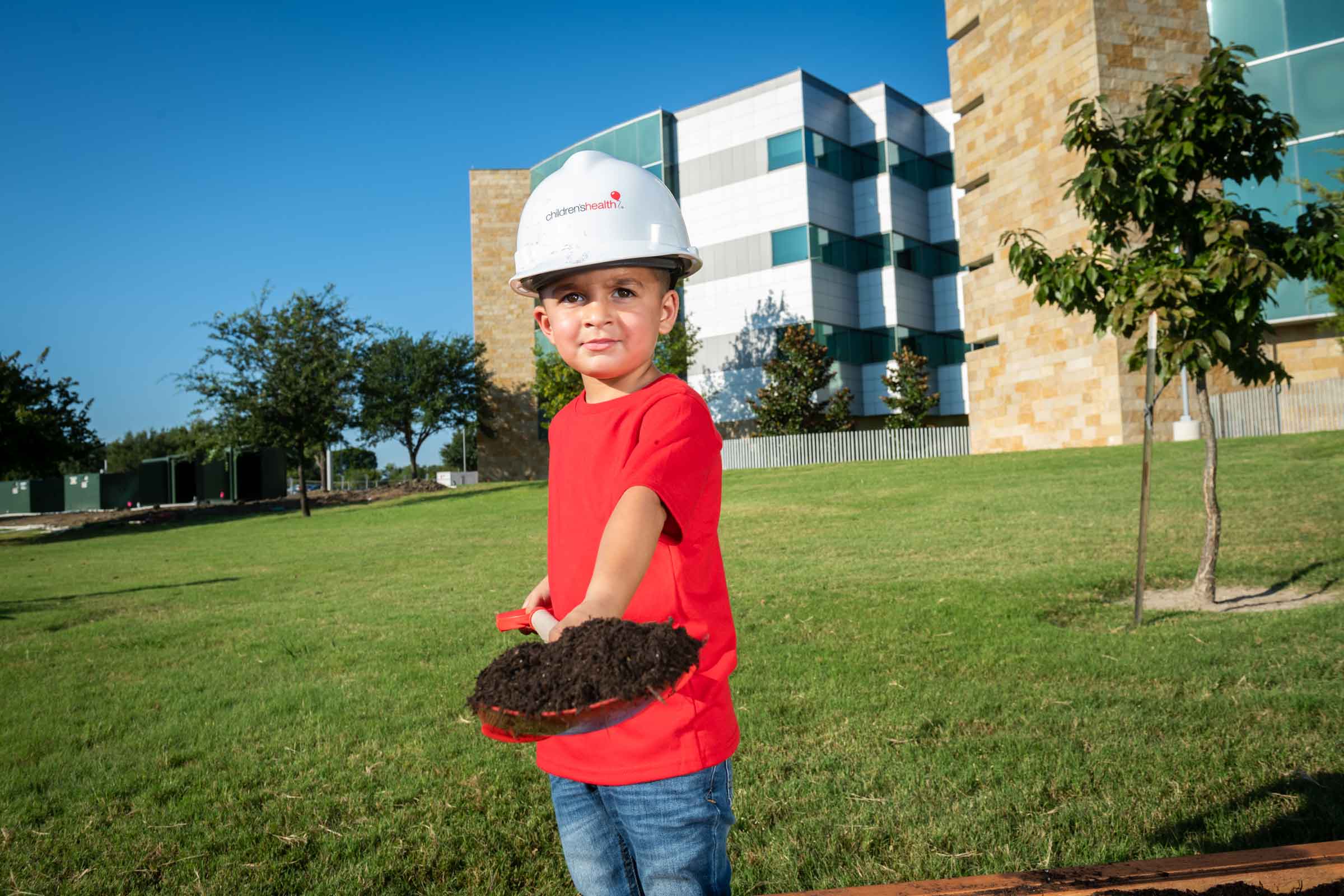 A child holds a shovel full of dirt at a groundbreaking ceremony
