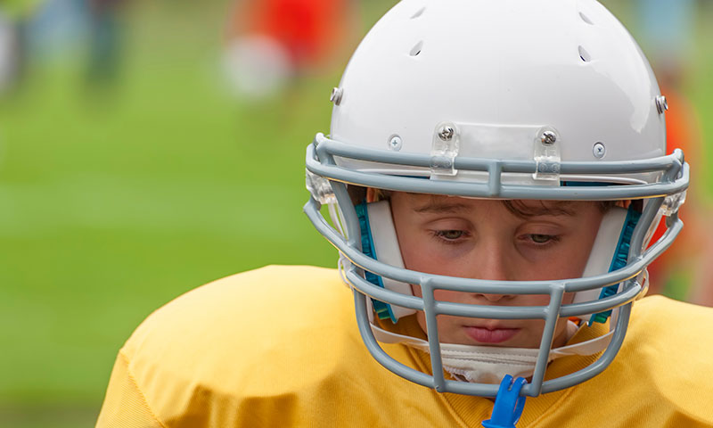 Young boy wearing football gear.