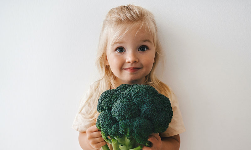 Girl holding a large bundle of broccoli